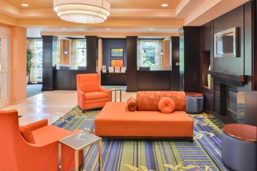 a lobby with orange chairs and a couch and a fireplace at Fairfield by Marriott Tacoma Puyallup in Puyallup
