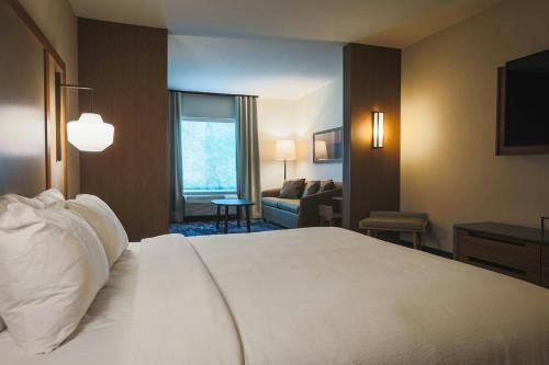 a hotel room with a bed and a living room at Fairfield Inn & Suites Marquette in Marquette