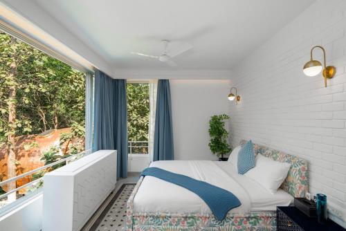 a bedroom with a bed and a large window at Verona by Vianaar Luxe Garden Pool Villa Assagao in Goa