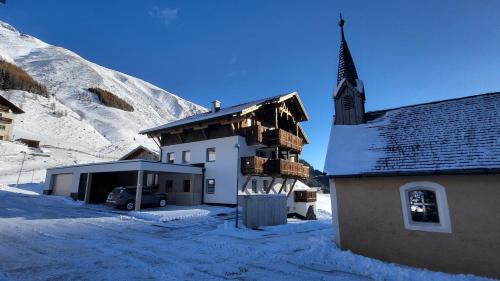 a building in the snow with a church at HAGGNER Hideaway in Sankt Sigmund im Sellrain