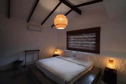 a bedroom with a white bed and a chandelier at Lunar Villas Koh Tao - Luxury Private Pool Villas in Koh Tao