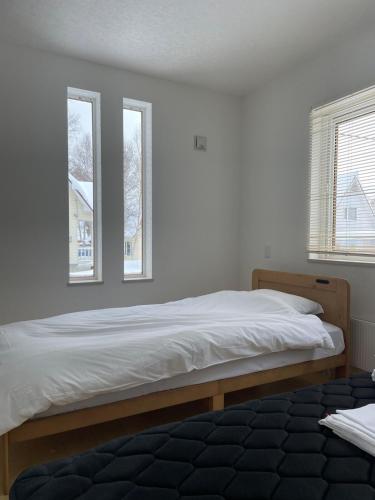 a bedroom with a large bed with two windows at Niseko Yu Villa C in Niseko