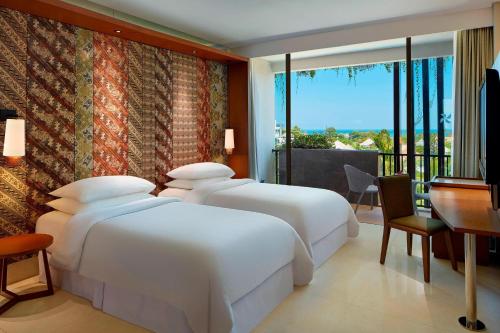 two beds in a hotel room with a balcony at Four Points by Sheraton Bali, Seminyak in Seminyak