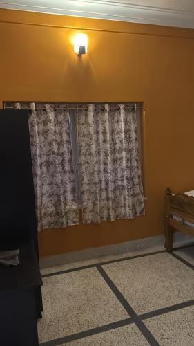a room with a window with a curtain and a lamp at The Tranquil Stay in kolkata