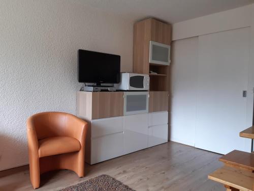 un salon avec une télévision et une chaise dans l'établissement Joli studio aux Carroz d'Arâches, à Arâches-la-Frasse