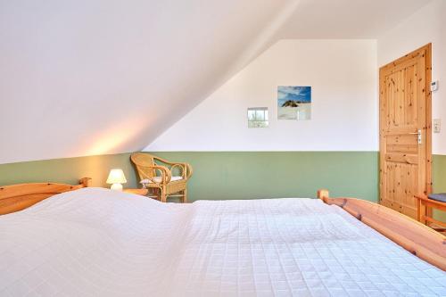 a bedroom with a large white bed and a chair at Am Redensee in Fuhlendorf