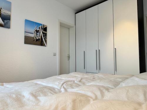 a bedroom with a white bed with a picture on the wall at Küsten Koje in Sankt Peter-Ording