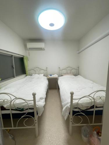 two beds in a room with a light on the ceiling at Tokyo Shibya 88 Shared House in Tokyo