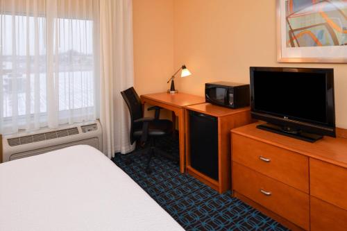 a hotel room with a bed and a desk with a television at Fairfield Inn and Suites by Marriott Fort Wayne in Fort Wayne