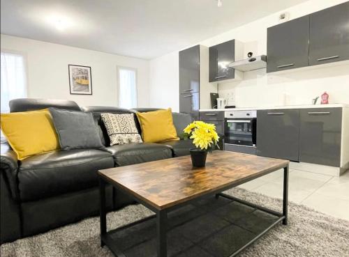 un salon avec un canapé noir et une table dans l'établissement Appartement - Le Salengro, à Villeurbanne