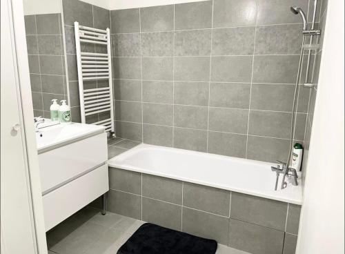 une salle de bain avec une baignoire et un lavabo dans l'établissement Appartement - Le Salengro, à Villeurbanne