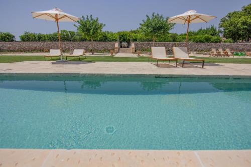 2 sillas y sombrillas junto a una piscina en Masseria Abbracciavento - Private Pool by HDSalento, en Tricase