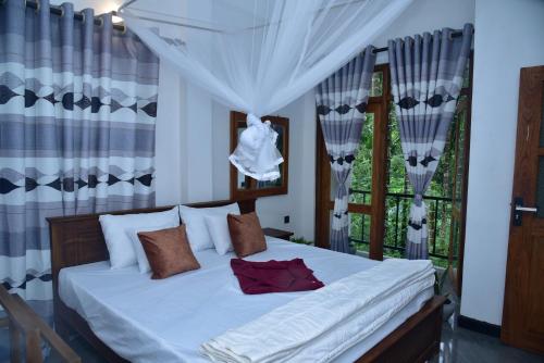 a bedroom with a white bed with curtains and a window at Ella Woodland 3 Arch Cottage in Ella