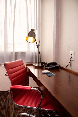 an office with a red chair and a desk with a lamp at Four Points by Sheraton Queretaro Norte in Querétaro