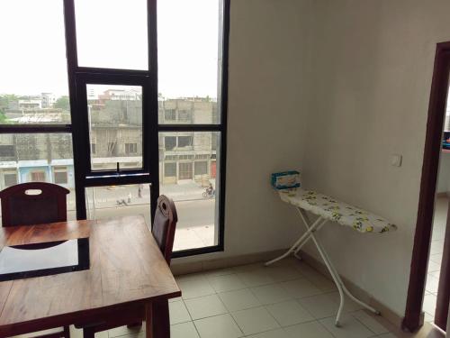 a room with a table and a chair and windows at Tadagbe Appart Studio1 in Cotonou