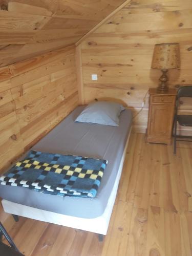 a bed in a wooden cabin with a lamp at gite D ETAPE DU PELERIN de la butte aux oiseaux in Saint-Alban-sur-Limagnole