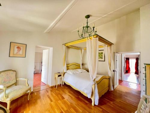 une chambre avec un lit à baldaquin et une chaise dans l'établissement Domaine de la Clapière, à Montagnac