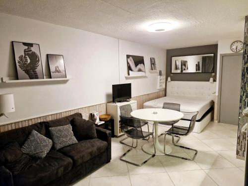 un salon avec un canapé, une table et un lit dans l'établissement Village naturiste Beach Place, au Cap d'Agde