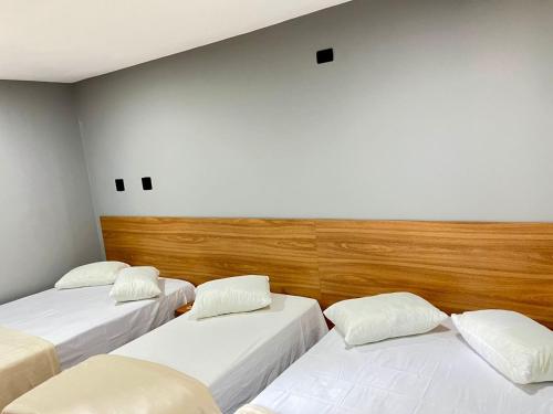 two beds in a room with white walls at Santa Rita Pousada in Guarujá