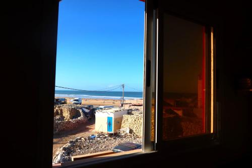 a window with a view of a city and the ocean at Little Beach House Sidi Kaouki in Sidi Kaouki