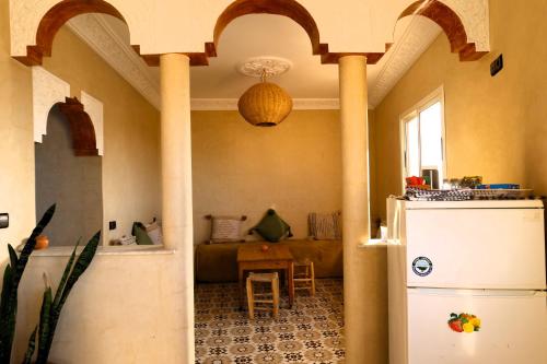 a living room with a refrigerator and a table at Little Beach House Sidi Kaouki in Sidi Kaouki