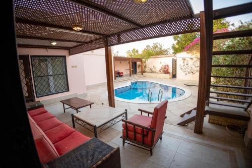 a patio with a pool and a couch and a table at Andalusia Blue Beach Hurghada in Hurghada