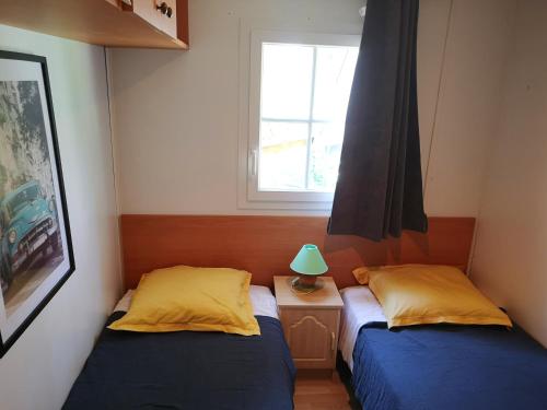 two beds in a small room with a window at Mobil-Home à louer dans le golfe de Saint-Tropez in Gassin