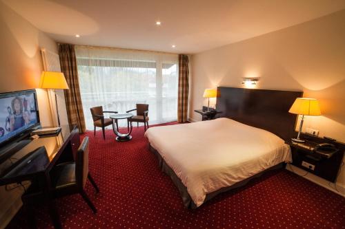 a hotel room with a bed and a table with chairs at Hôtel Beau Rivage in Gérardmer