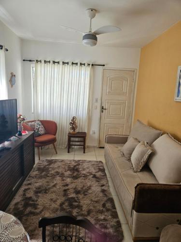 a living room with a couch and a tv at Chalé das Conchas in Cabo Frio