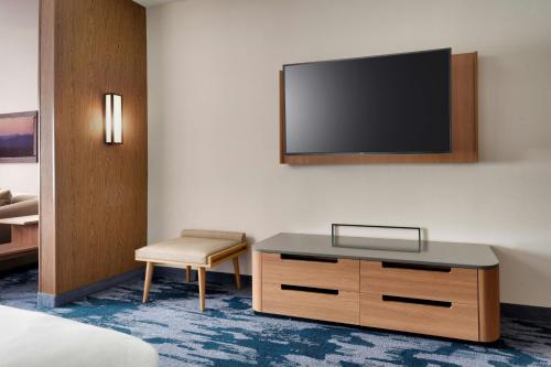 a hotel room with a tv on the wall and a chair at Fairfield by Marriott Inn & Suites Salt Lake City Cottonwood in Holladay