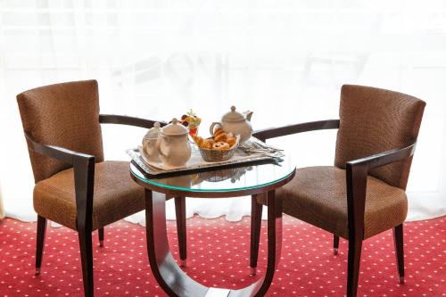 a table with two chairs and a bowl of fruit on it at Hôtel Beau Rivage in Gérardmer