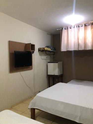 a bedroom with a bed and a flat screen tv at Hotel Galli in Campo Grande