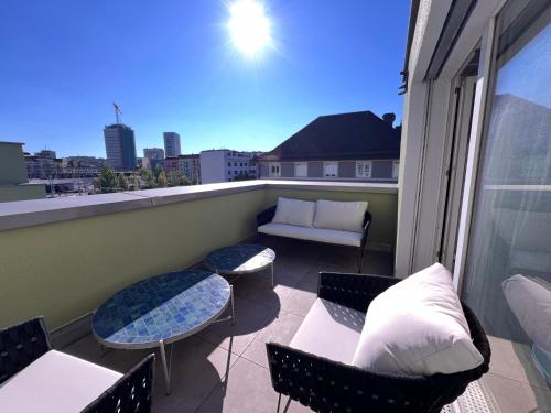 a balcony with a couch and chairs on a balcony at UP&GREAT Apartments - Stylish City Living in Zürich