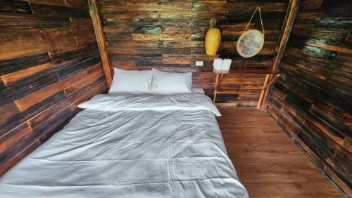 a small bed in a room with wooden walls at Sùng A Hờ Homestay in Mù Cang Chải