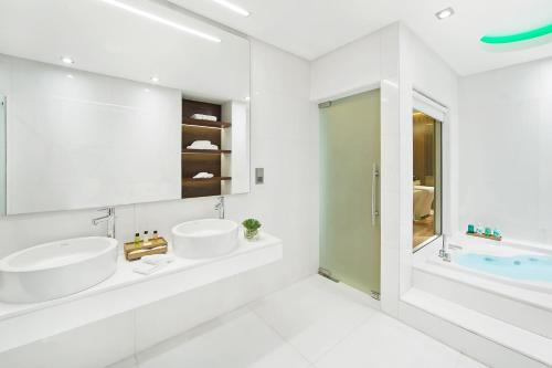 a white bathroom with two sinks and a tub at Four Points by Sheraton Doha in Doha
