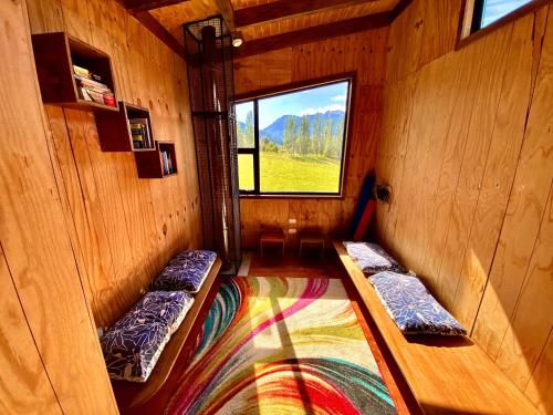 a room with two beds in a room with a window at Hostal Las Natalias in Futaleufú
