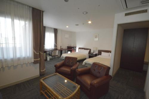 a hotel room with two beds and two chairs at Hotel Soleil in Iwaki