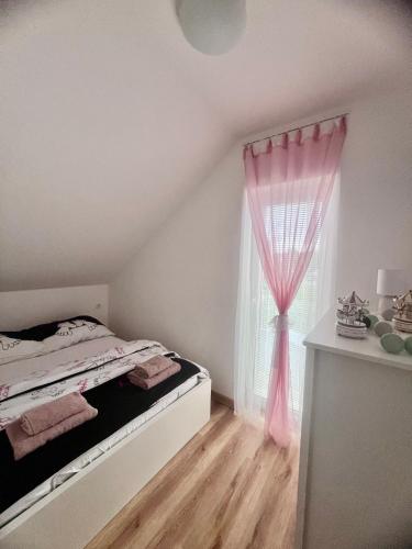 a bedroom with a bed and a window with pink curtains at Apartmán Roda2 Malé Lipno in Černá v Pošumaví