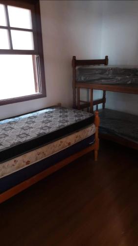two beds in a room with a window at Casa de praia in Itanhaém