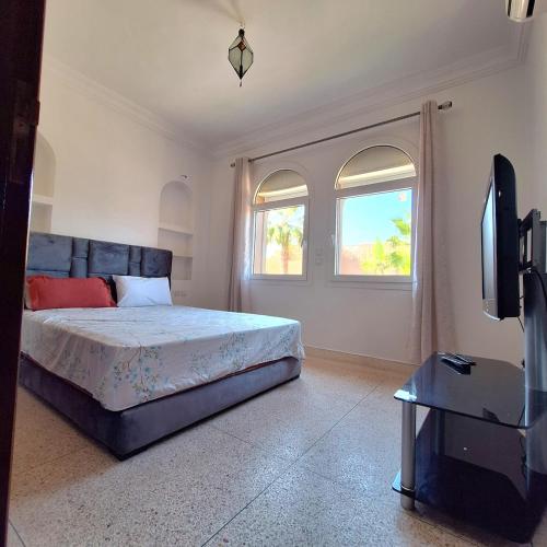 a bedroom with a bed and a flat screen tv at Azure Horizon Villa Club evasion in Sidi Boulfdail