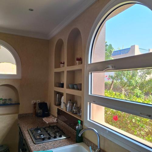 a kitchen with two windows and a stove and a sink at Azure Horizon Villa Club evasion in Sidi Boulfdail