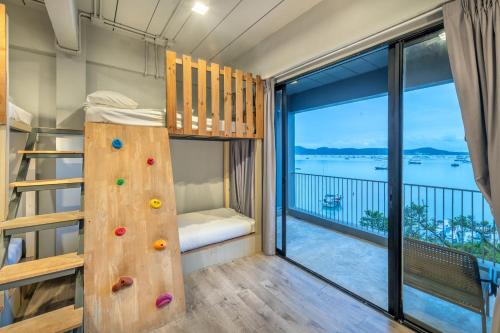 a room with a bunk bed and a balcony at SHIN Arch39 Phuket Beach Front - SHA Plus in Chalong 