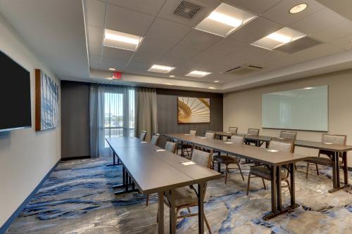 a conference room with tables and chairs and a screen at Fairfield Inn & Suites Warsaw in Warsaw