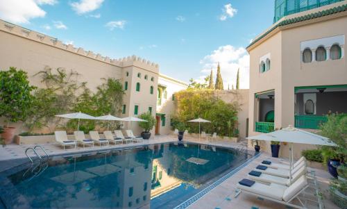 - une piscine avec des chaises et des parasols à côté d'un bâtiment dans l'établissement Palais Faraj Suites & Spa, à Fès