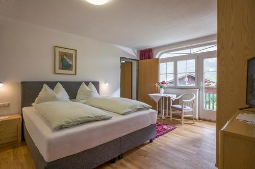 a bedroom with a large bed and a dining room at Apparthotel Tom Sojer in Ellmau