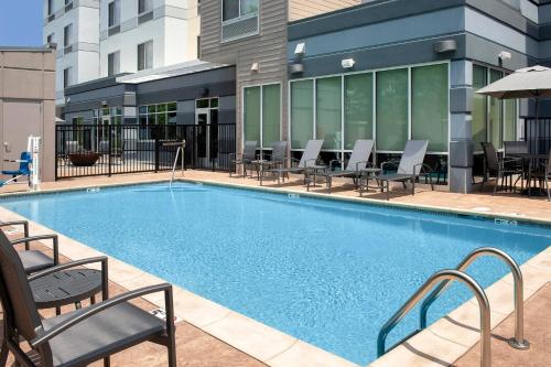 a swimming pool with chairs and tables and a building at Fairfield Inn & Suites by Marriott Knoxville Lenoir City/I-75 in Lenoir City