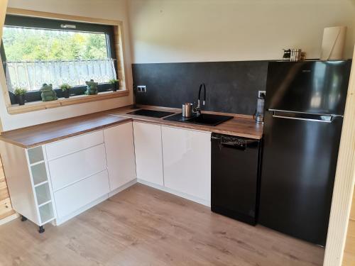 a kitchen with a black refrigerator and white cabinets at Hortensja in Rusinowo