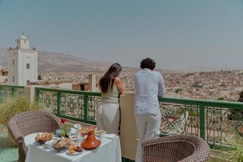 a man and woman standing on a balcony looking at a city at Palais Faraj Suites & Spa in Fès