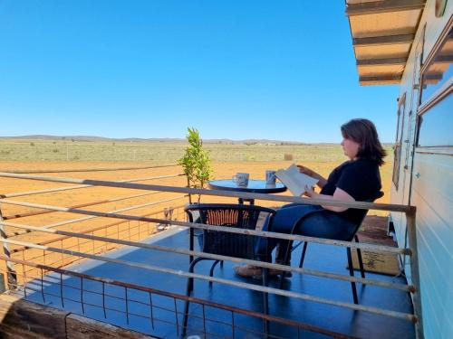 een vrouw die op een balkon zit een boek te lezen bij Quentin Park Hideaway 1 in Peterborough