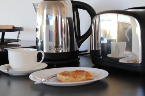 een bord met een stuk eten op een tafel naast een koffiepot bij Quentin Park Hideaway 1 in Peterborough